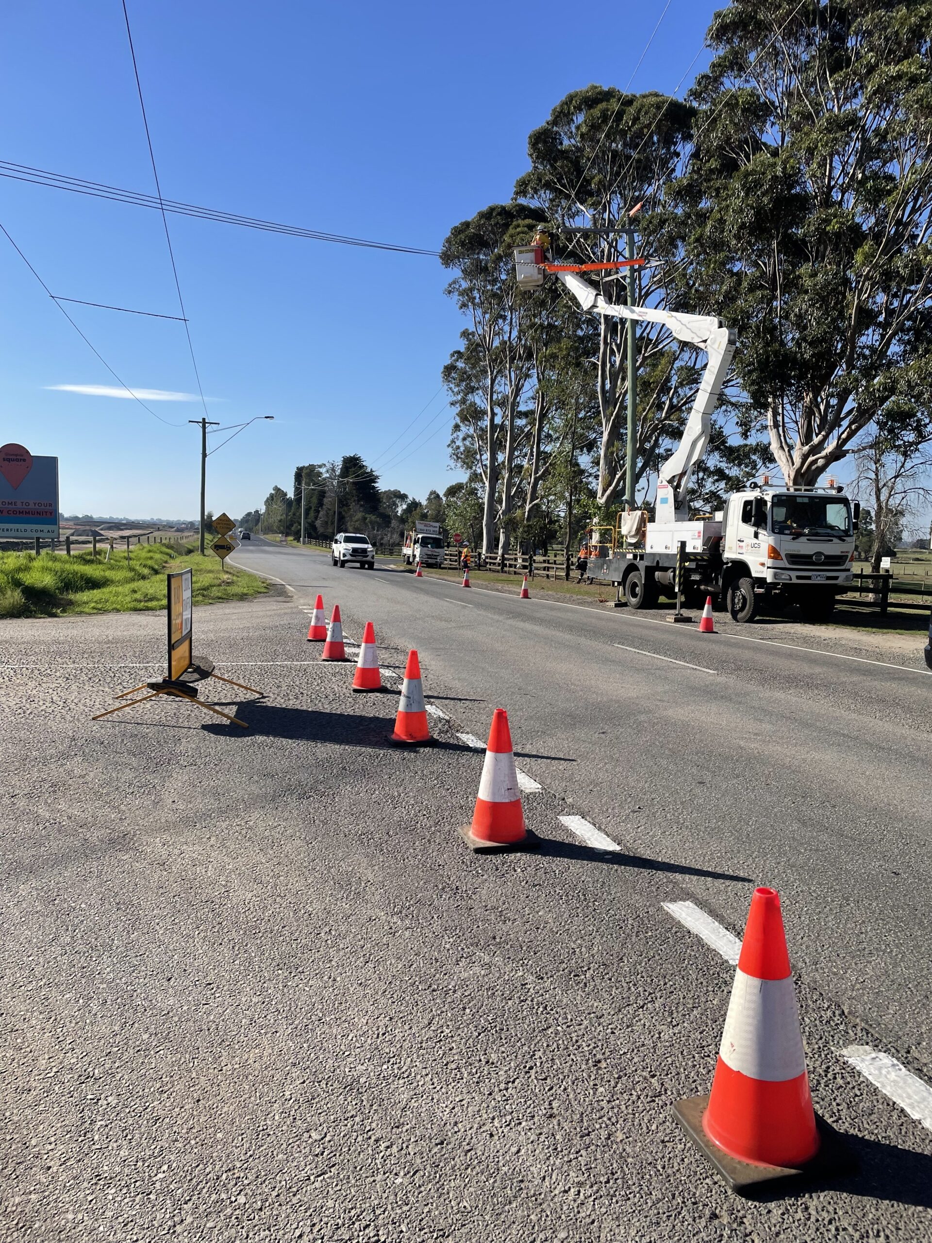 Utility crew using a bucket truck for overhead line maintenance on a rural roadside