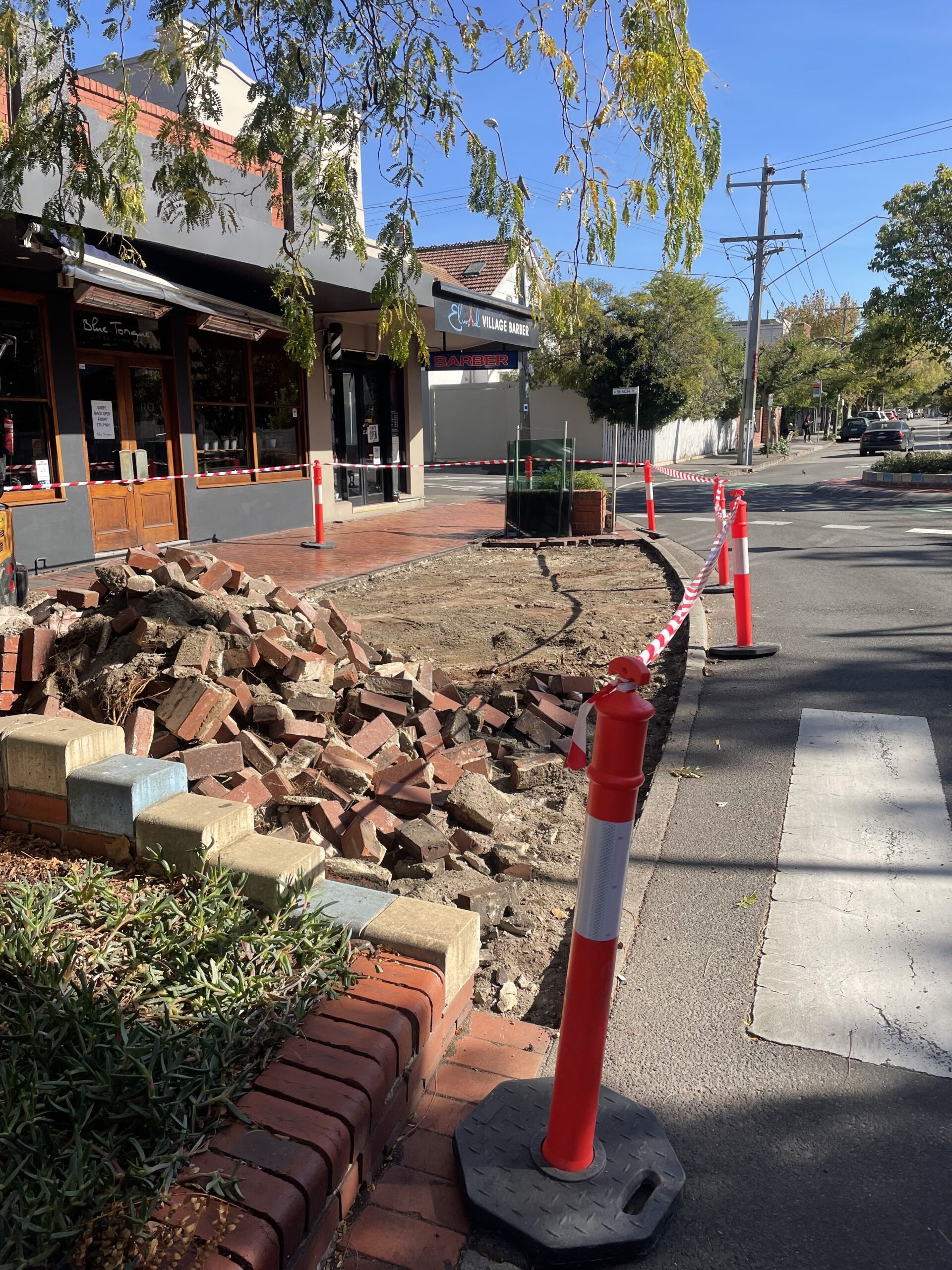 Sidewalk excavation site marked with safety cones for underground utility or fiber installation
